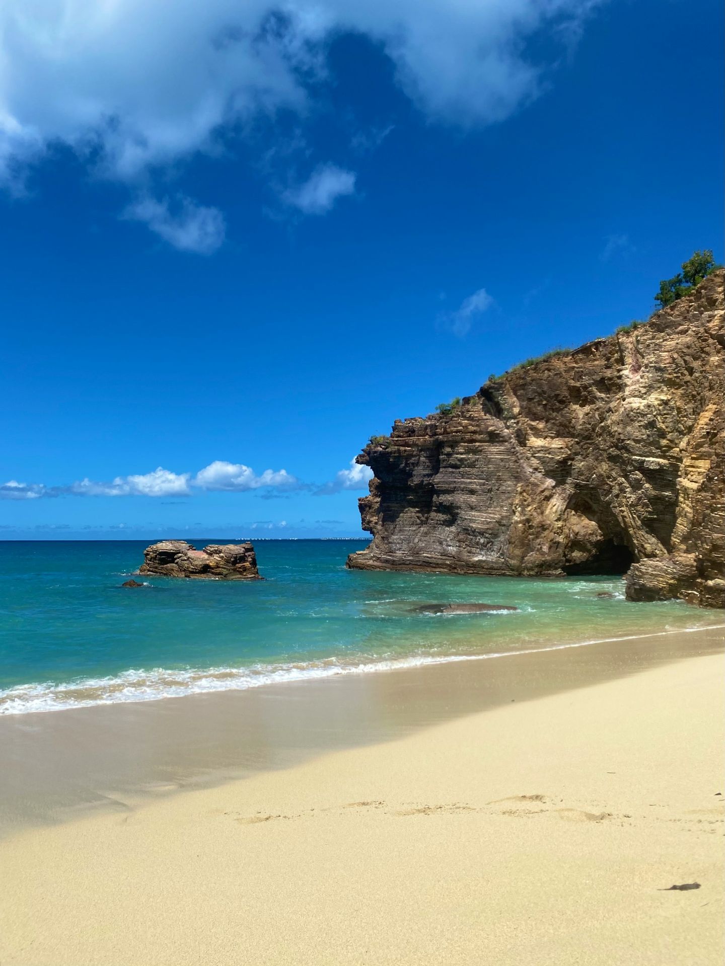 a sandy beach next to the ocean under a blue sky